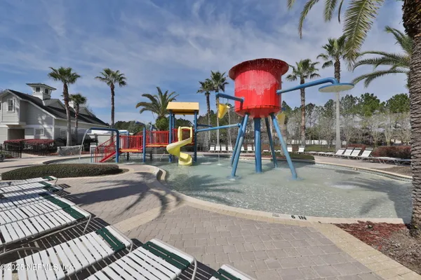 a view of swimming pool that has lawn chairs with plants and trees