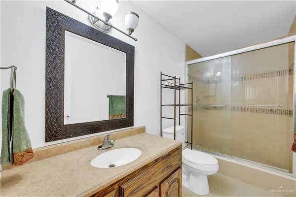 a bathroom with a granite countertop sink toilet a mirror and shower
