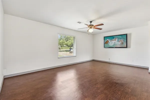 an empty room with windows and chandelier fan