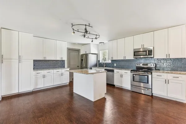 a kitchen with granite countertop white cabinets and stainless steel appliances