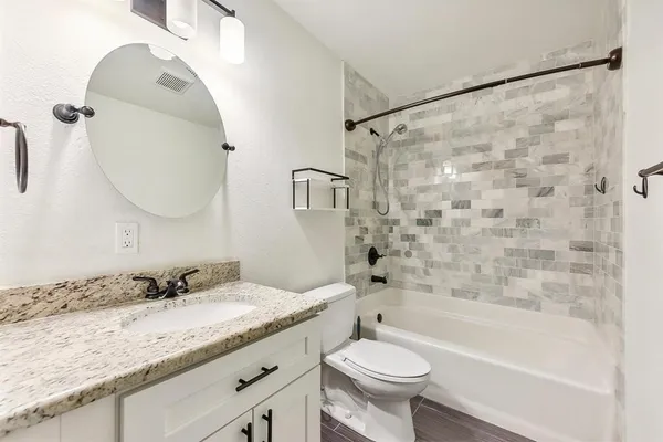 a bathroom with a granite countertop sink a toilet and shower