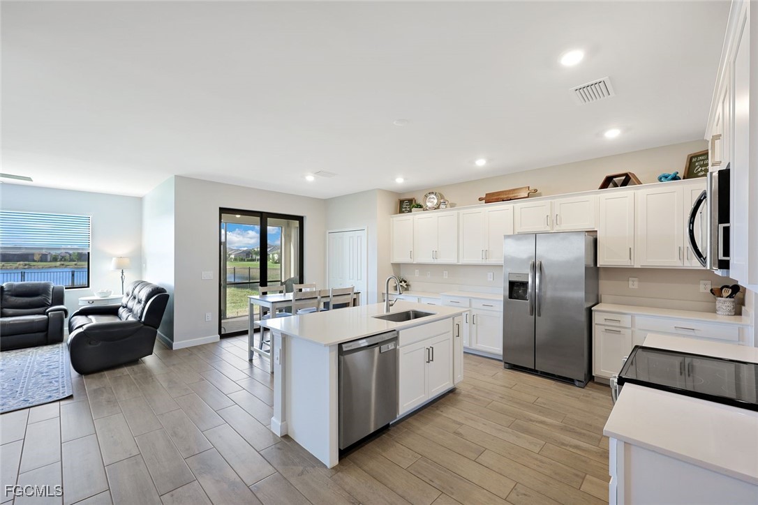 11087 Canopy Loop Fort Myers, FL 33913 - Photo 7 of 48 a kitchen with stainless steel appliances kitchen island granite countertop a refrigerator a sink dishwasher a stove and a dining table with wooden floor