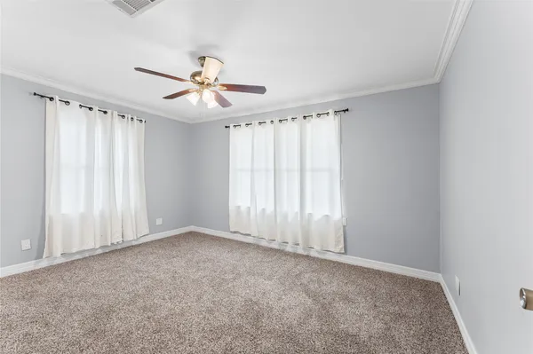 an empty room with chandelier fan and windows