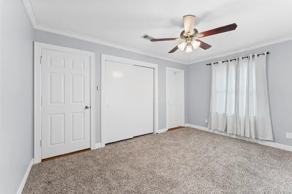 a view of an empty room and chandelier fan