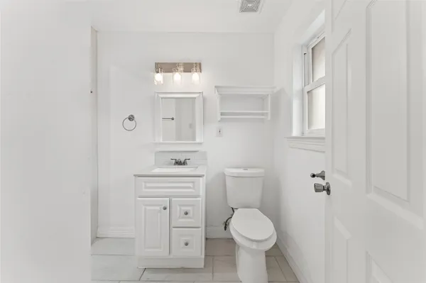 a bathroom with a granite countertop toilet a sink and a mirror