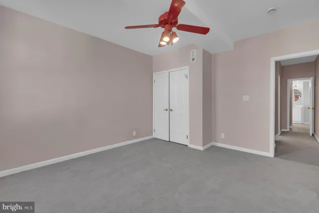 an empty room with closet and a chandelier fan