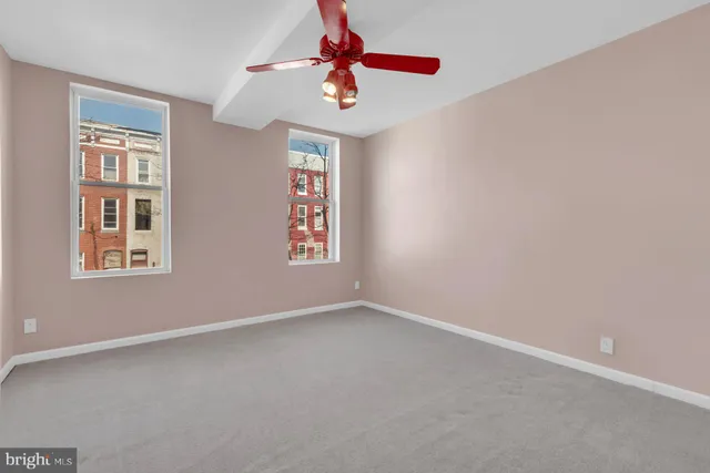 an empty room with windows and fan