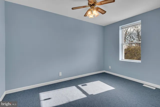 an empty room with windows and fan