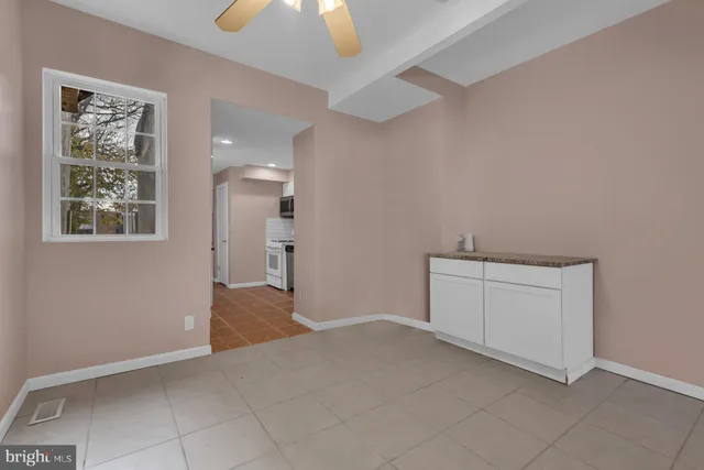 a view of an empty room and chandelier fan