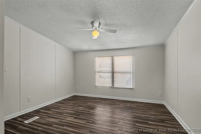 an empty room with wooden floor and ceiling fan