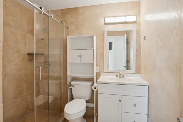 a bathroom with a shower sink vanity mirror and toilet