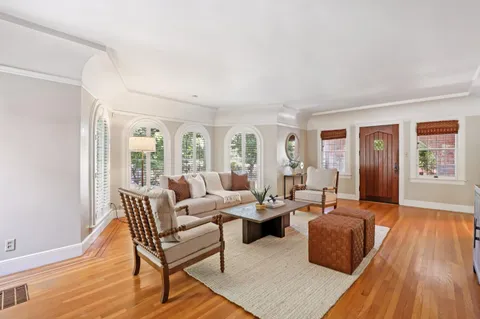 a dining room with wooden floor a chandelier a wooden table and chairs