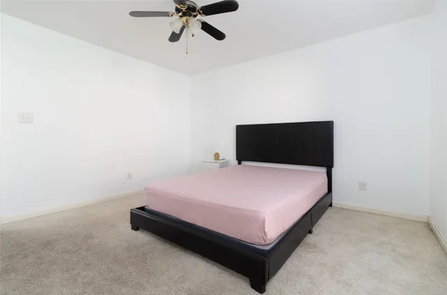 a spacious bedroom with a bed and a chandelier fan