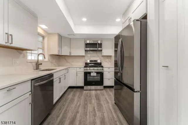 a kitchen with stainless steel appliances a refrigerator sink and white cabinets