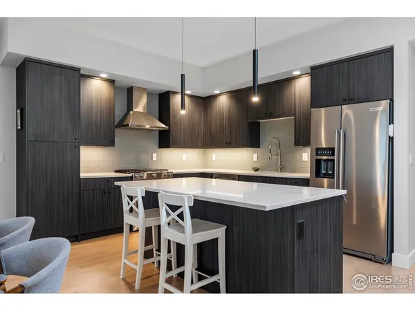 a kitchen with stainless steel appliances kitchen island a table chairs in it and wooden floors
