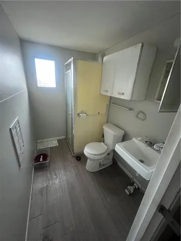 a view of a hallway with wooden floor and a bathroom