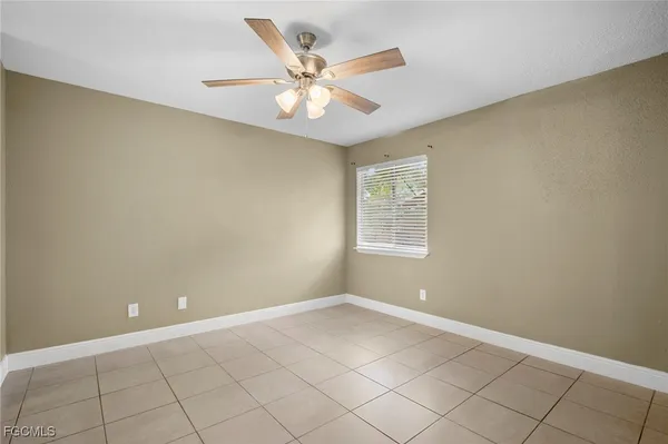 an empty room with a ceiling fan and window