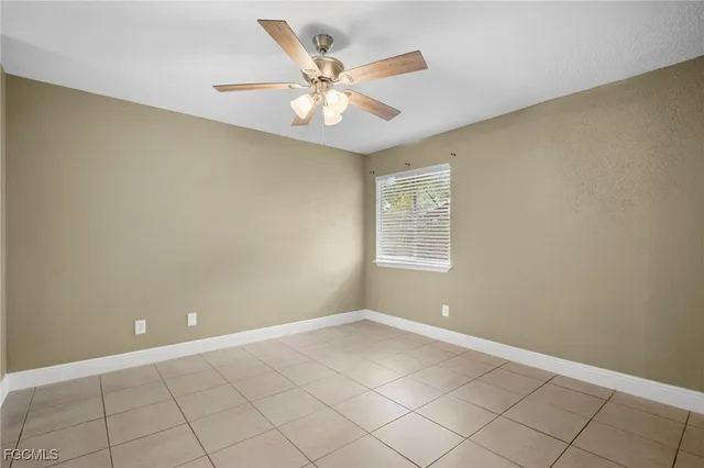 an empty room with a ceiling fan and window