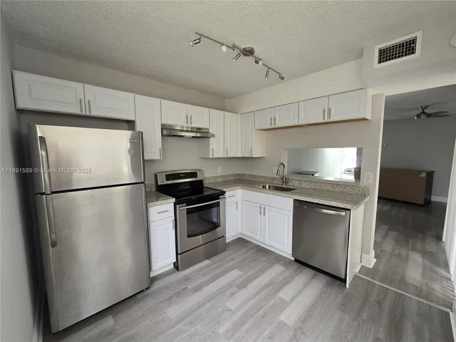 a kitchen with granite countertop a refrigerator stove top oven and sink