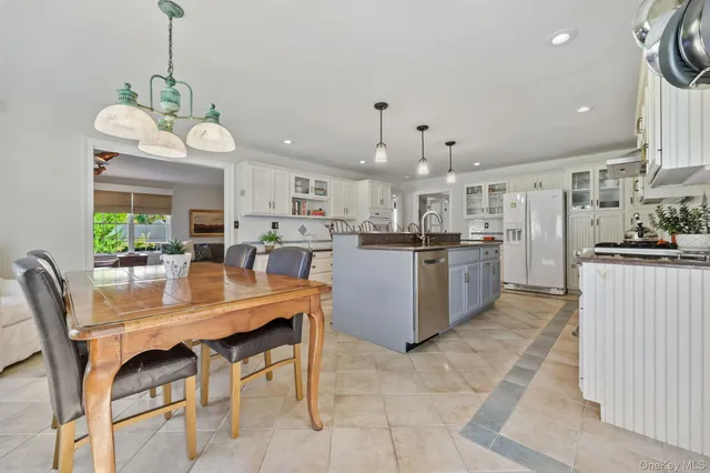 a kitchen with stainless steel appliances kitchen island granite countertop a table chairs and a refrigerator