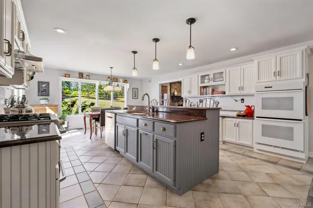 a kitchen with kitchen island granite countertop lots of white stainless steel appliances cabinets and a stove top oven