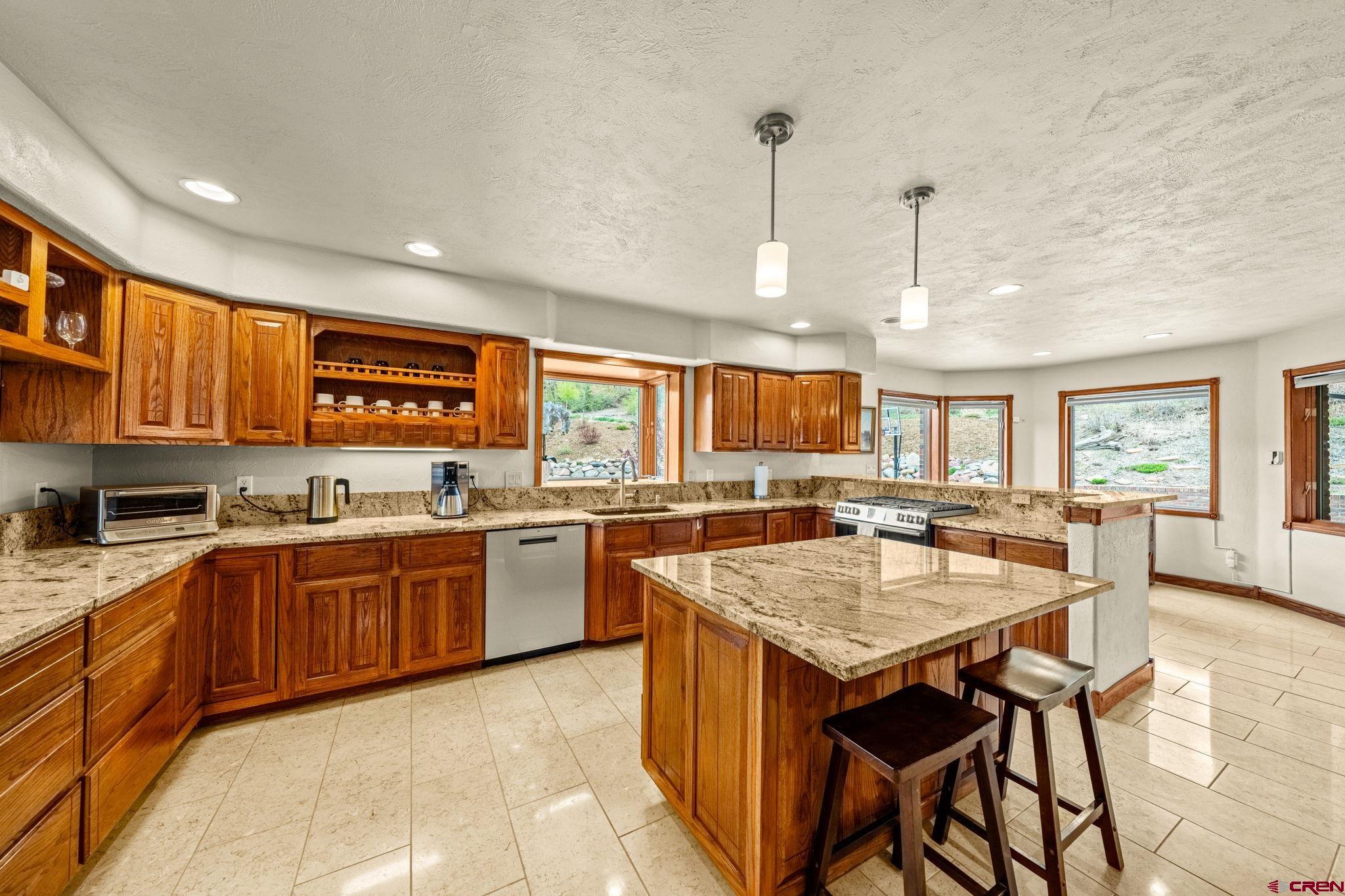 201 Ute Canyon Road Durango, CO 81301 - Photo 32 of 44 a large kitchen with kitchen island granite countertop a stove a sink a dining table and chairs with wooden floor
