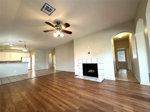 a view of an empty room with kitchen and a fireplace