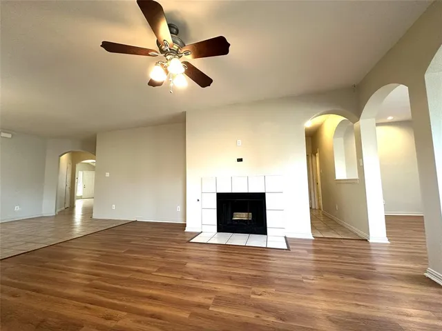 a view of an empty room with wooden floor and a fireplace
