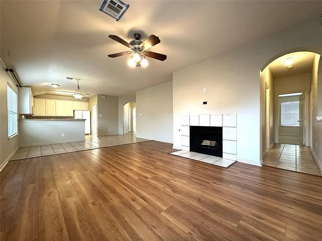 a view of an empty room with wooden floor and a fireplace