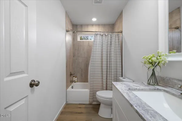 a bathroom with a granite countertop sink a toilet and shower