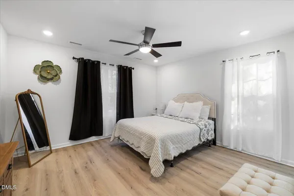 a bedroom with a bed a dresser and a chandelier