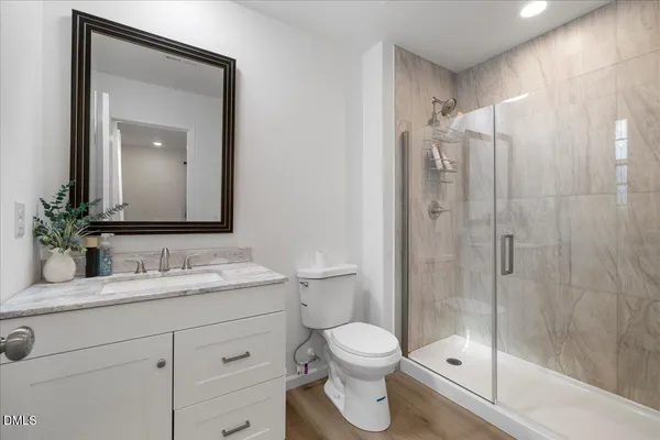 a bathroom with a shower sink vanity mirror and toilet