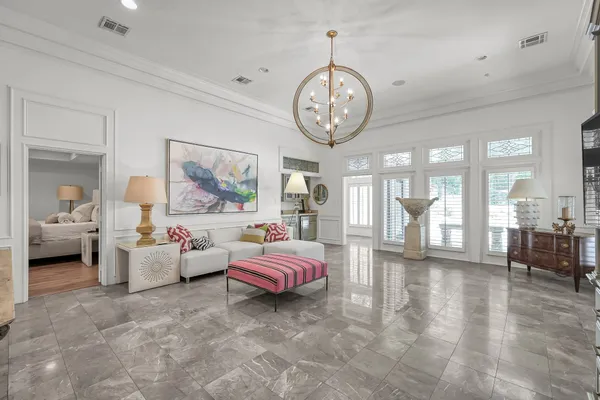 a spacious bedroom with a bed a chandelier and a large window