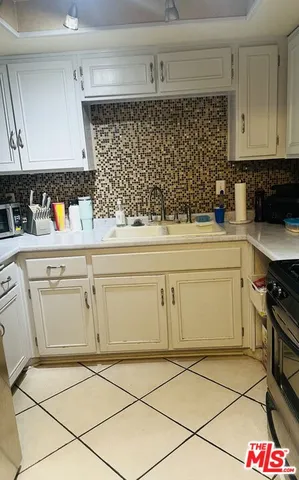 a kitchen with white cabinets and appliances