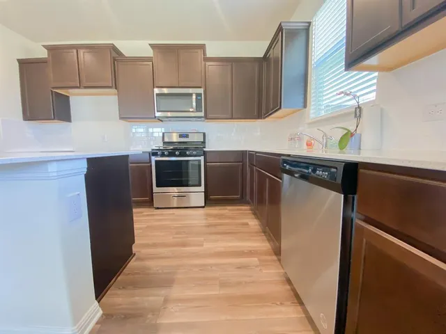 a kitchen with stainless steel appliances granite countertop a refrigerator a sink and a stove