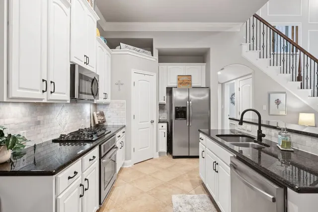 a kitchen with granite countertop a sink a stove top oven a dining table and chairs