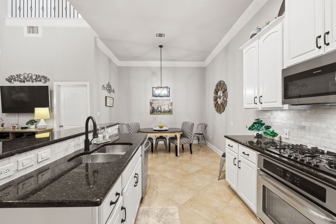 218 Sunrise Ridge Loop Lakeway, TX 78738 - Photo 9 of 40 a kitchen with granite countertop a sink a stove top oven a dining table and chairs