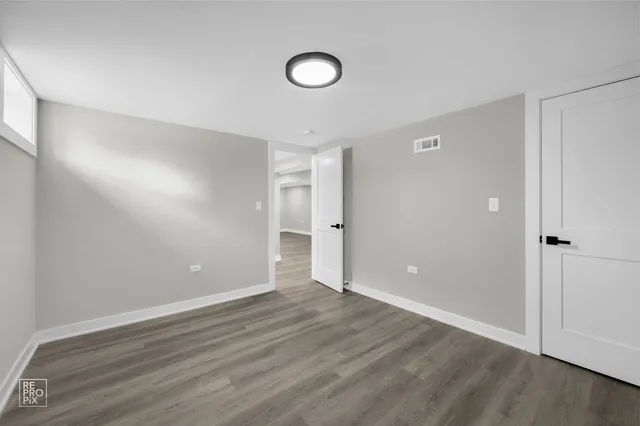 a view of an empty room with wooden floor and window