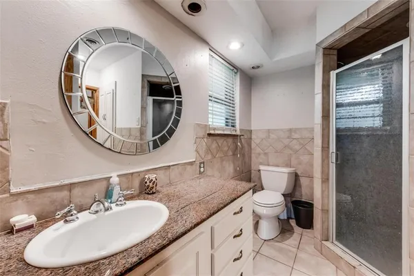 a bathroom with a granite countertop toilet a sink and a mirror