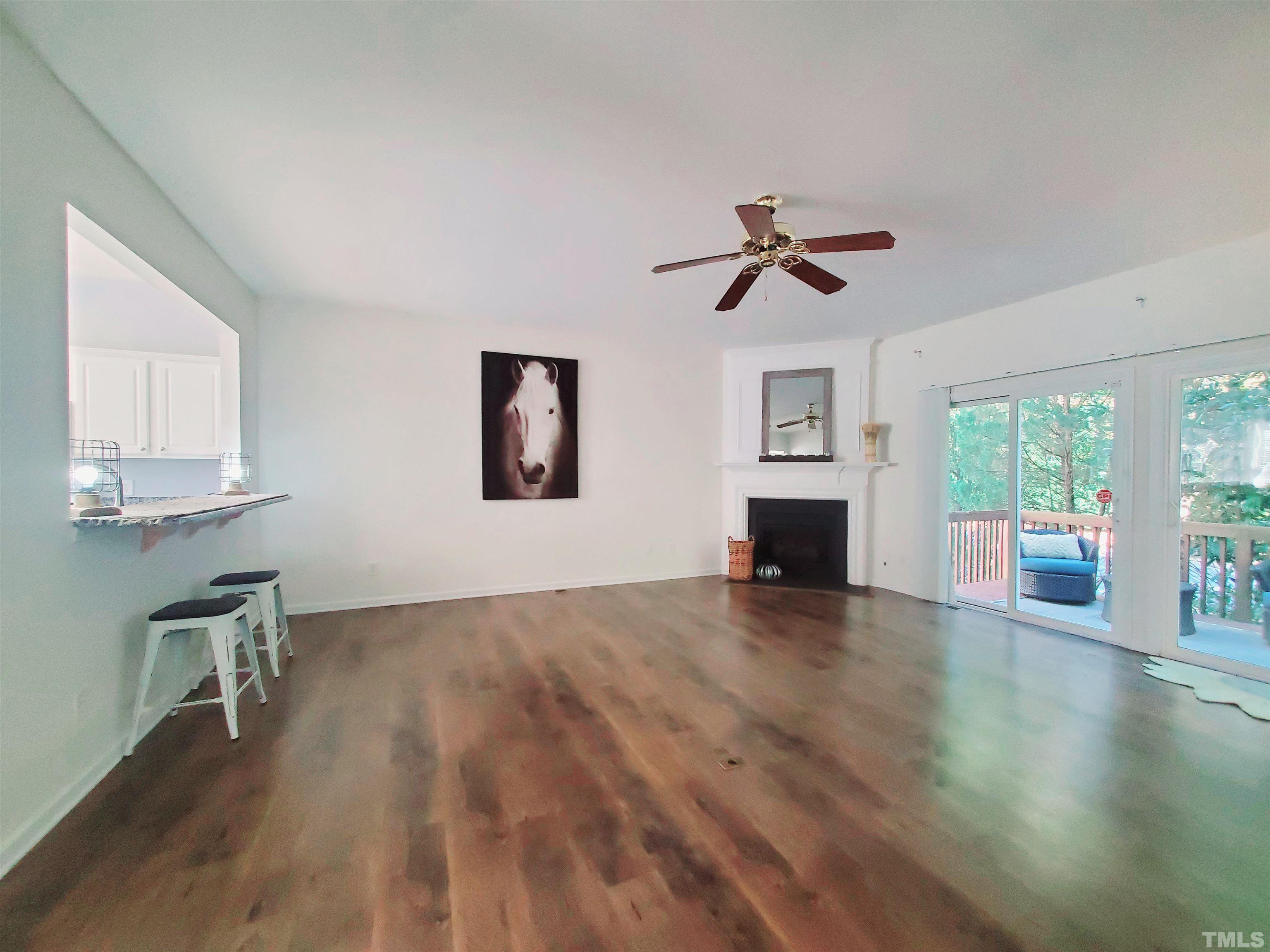 7236 Galon Glen Road Raleigh, NC 27613 - Photo 9 of 24 a view of a livingroom with a fireplace a ceiling fan and wooden floor