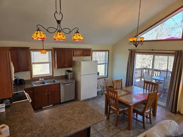 a kitchen with a refrigerator a stove dining table and chairs