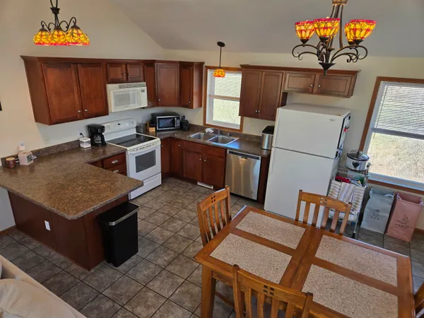 a kitchen with stainless steel appliances granite countertop a stove a refrigerator a sink dishwasher a dining table and chairs with wooden floor