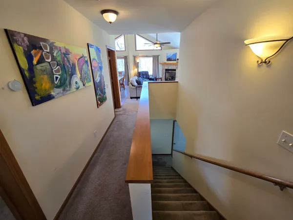 a view of a hallway with wooden floor and stairs