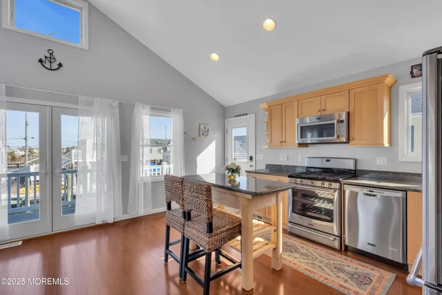 a kitchen with stainless steel appliances granite countertop a stove top oven a sink dishwasher a dining table and chairs with wooden floor