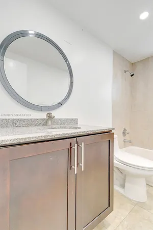 a bathroom with a granite countertop sink a toilet and a mirror