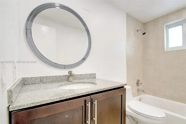 a bathroom with a granite countertop sink a toilet and a mirror