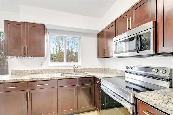 a kitchen with stainless steel appliances granite countertop a sink and a microwave