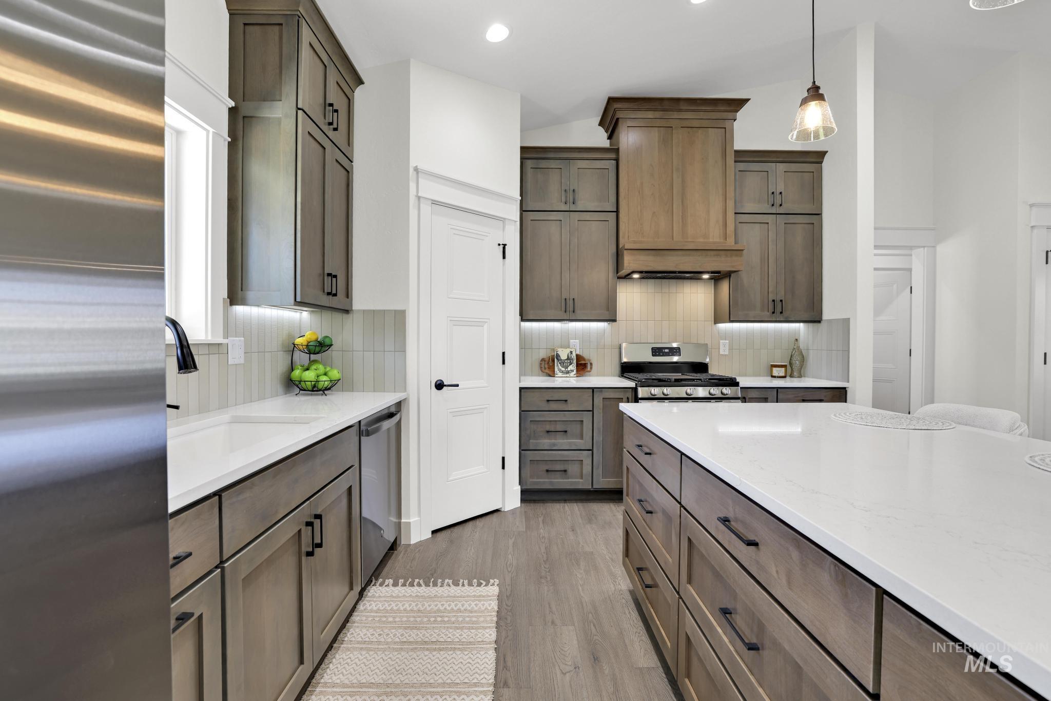 284 Sandi Road Twin Falls, ID 83301 - Photo 19 of 33 Utility space featuring wood-finish flooring, a white paneled door with matte black hardware, and two dark wood-finish wall-mounted cabinets