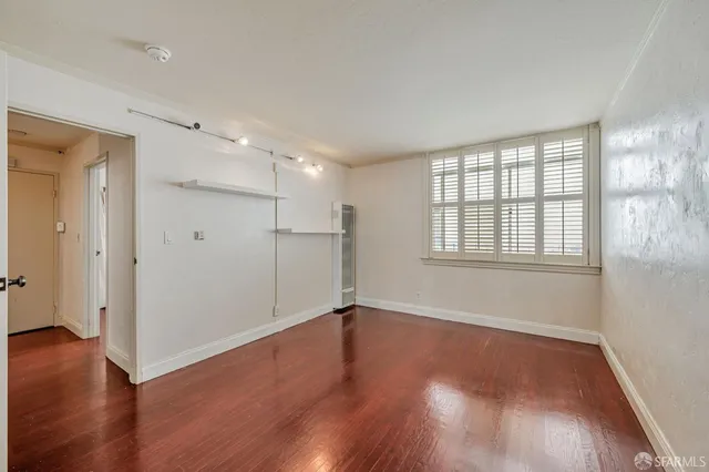 a view of an empty room with wooden floor and a window