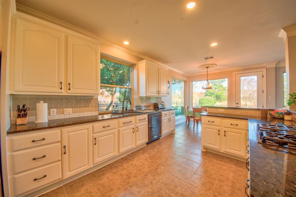730 East Peninsula Drive Coppell, TX 75019 - Photo 9 of 34 a large kitchen with granite countertop a large window and white cabinets